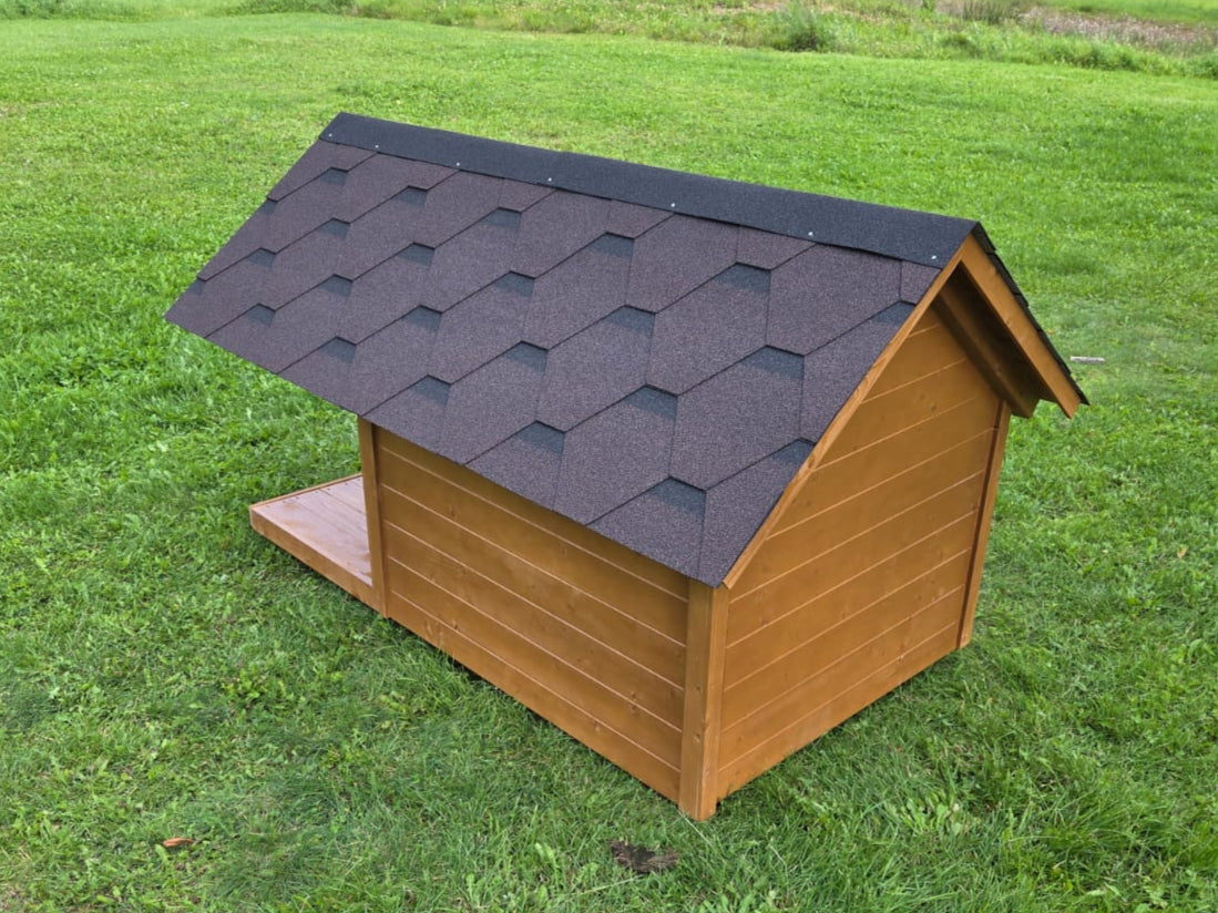 Wooden doghouse with a black roof on a grassy field