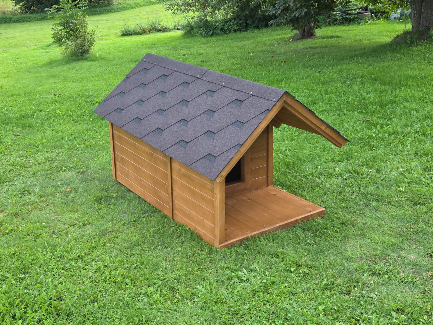 Wooden dog house with a gray roof on a grassy lawn