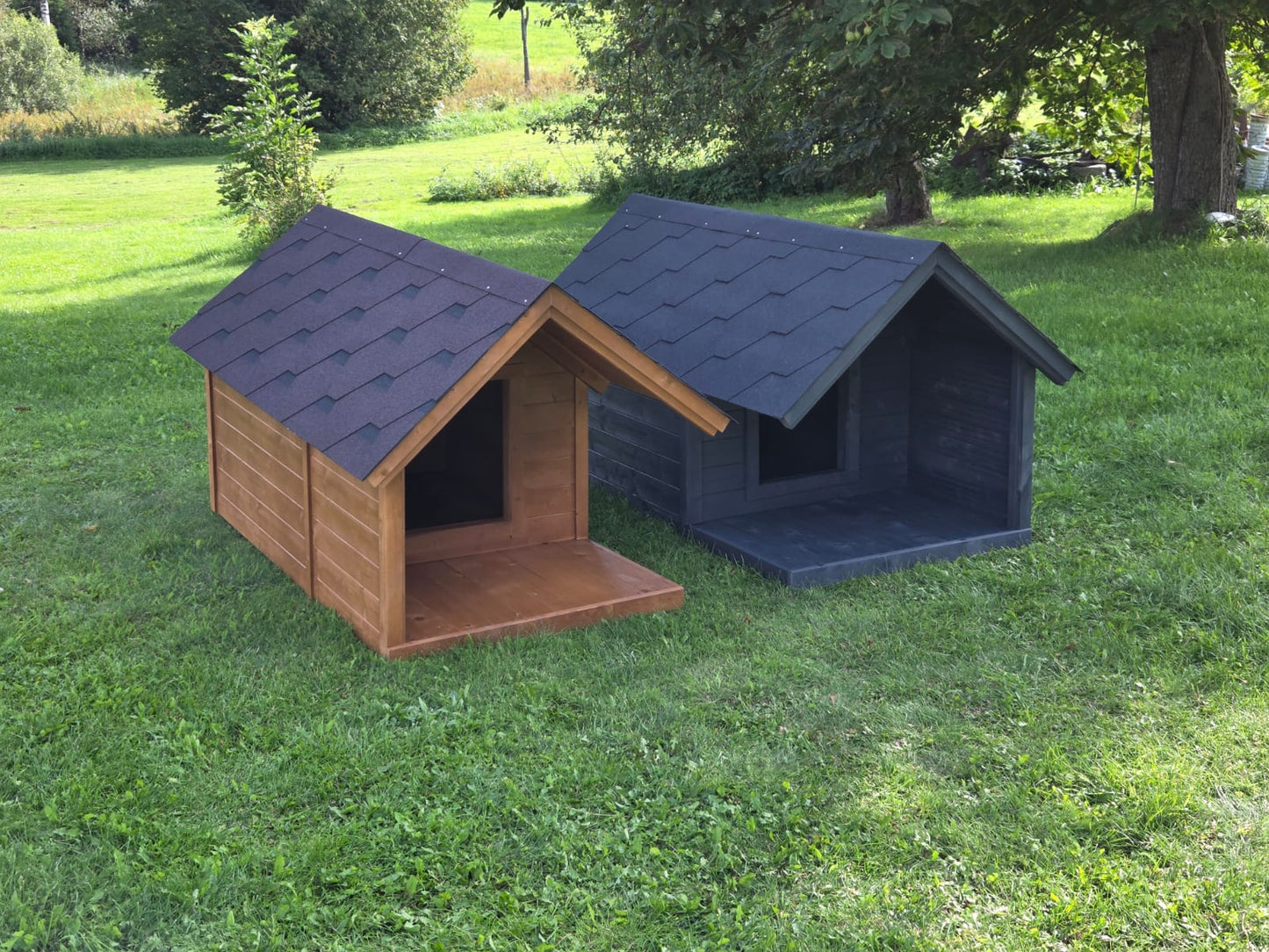 Two dog houses, one brown and one blue, on a grassy area with trees in the background.