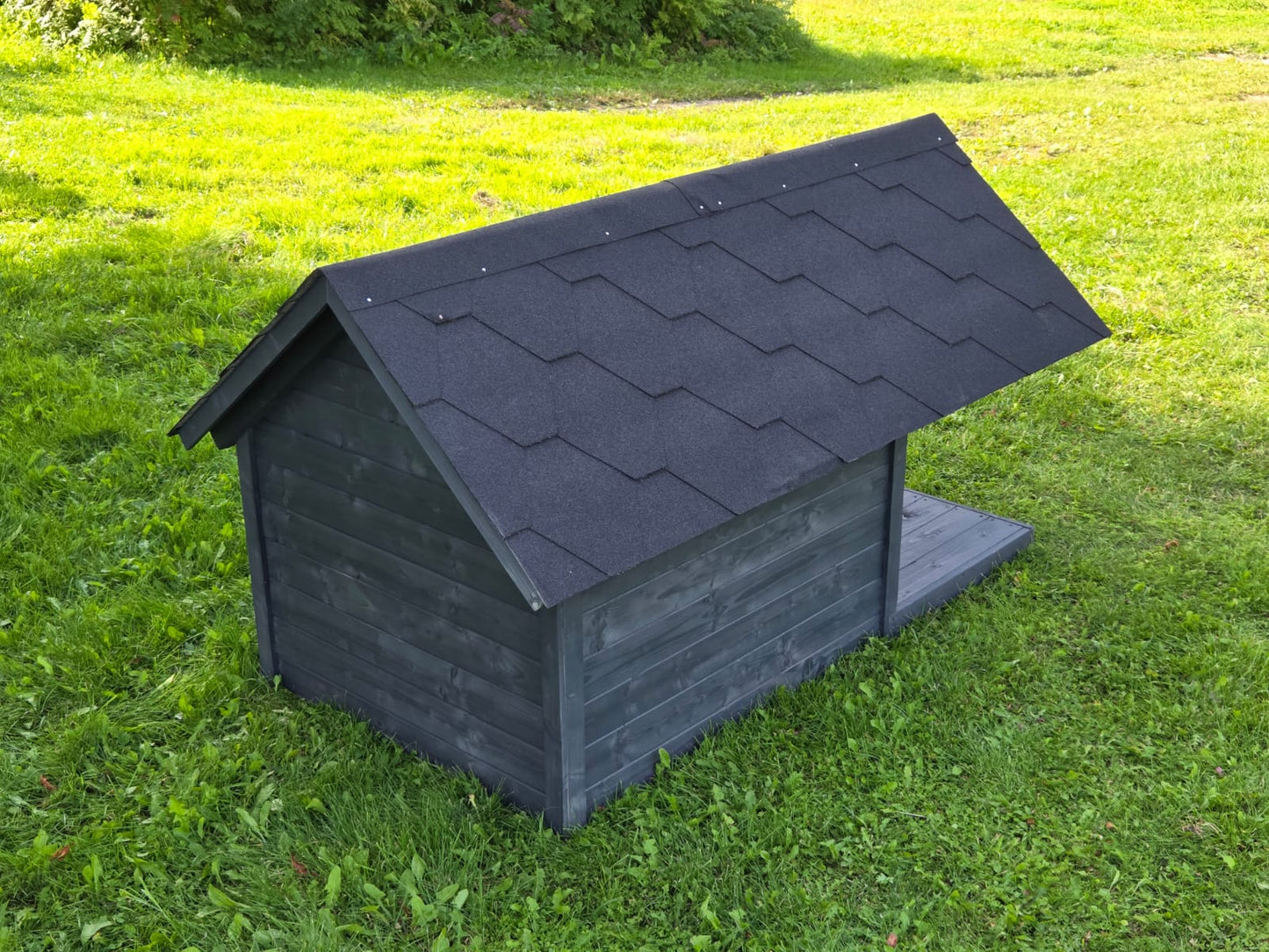 Black wooden dog house with a roof on grass