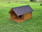 Wooden dog house with a black roof on a grassy field