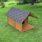 Wooden dog house with a gray roof on a grassy lawn