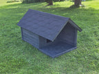 Dark gray dog house on a grassy lawn