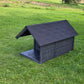 Black dog house on a grassy field