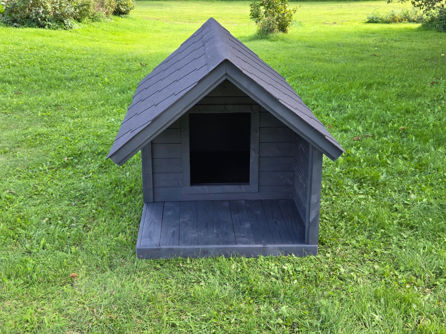 Gray dog house on a grassy field