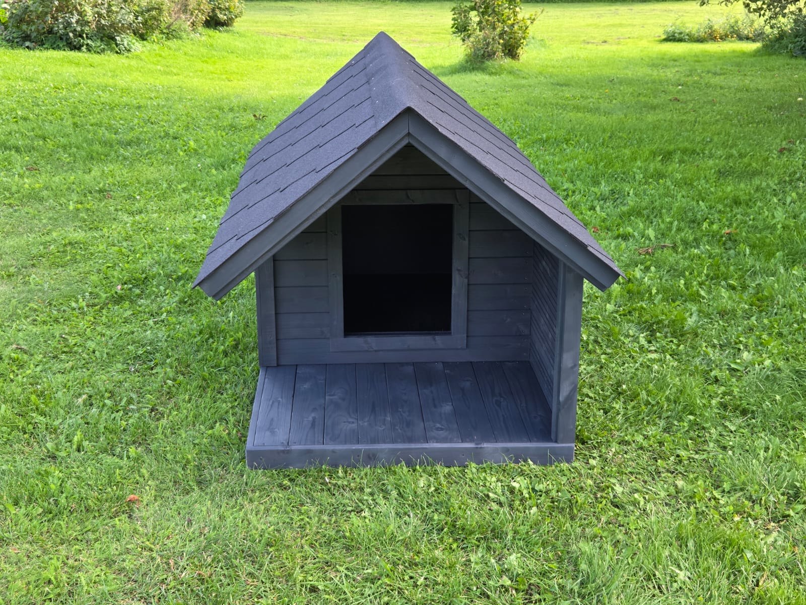 Gray dog house on a grassy field