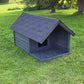 Dark gray dog house on a grassy area with trees in the background