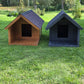 Two dog houses, one brown and one black, on a grassy field with trees in the background.