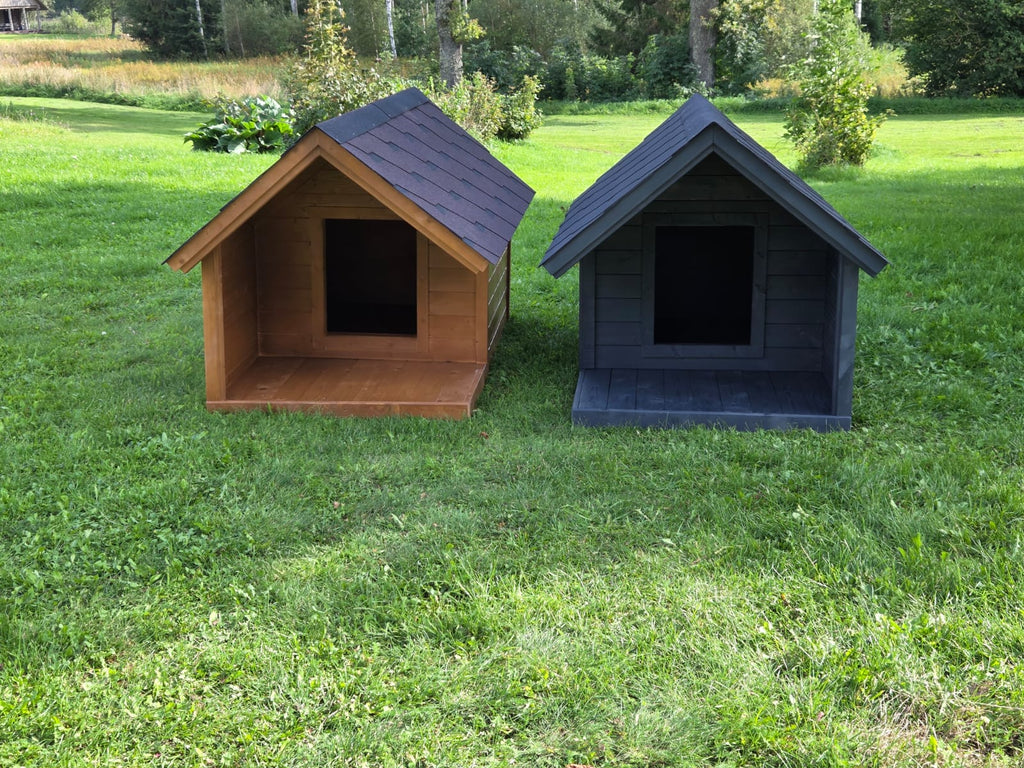 Two dog houses, one brown and one black, on a grassy field with trees in the background.
