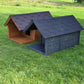 Two dog houses, one brown and one gray, on a grassy field.