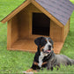 Dog sitting in front of a wooden doghouse on grass